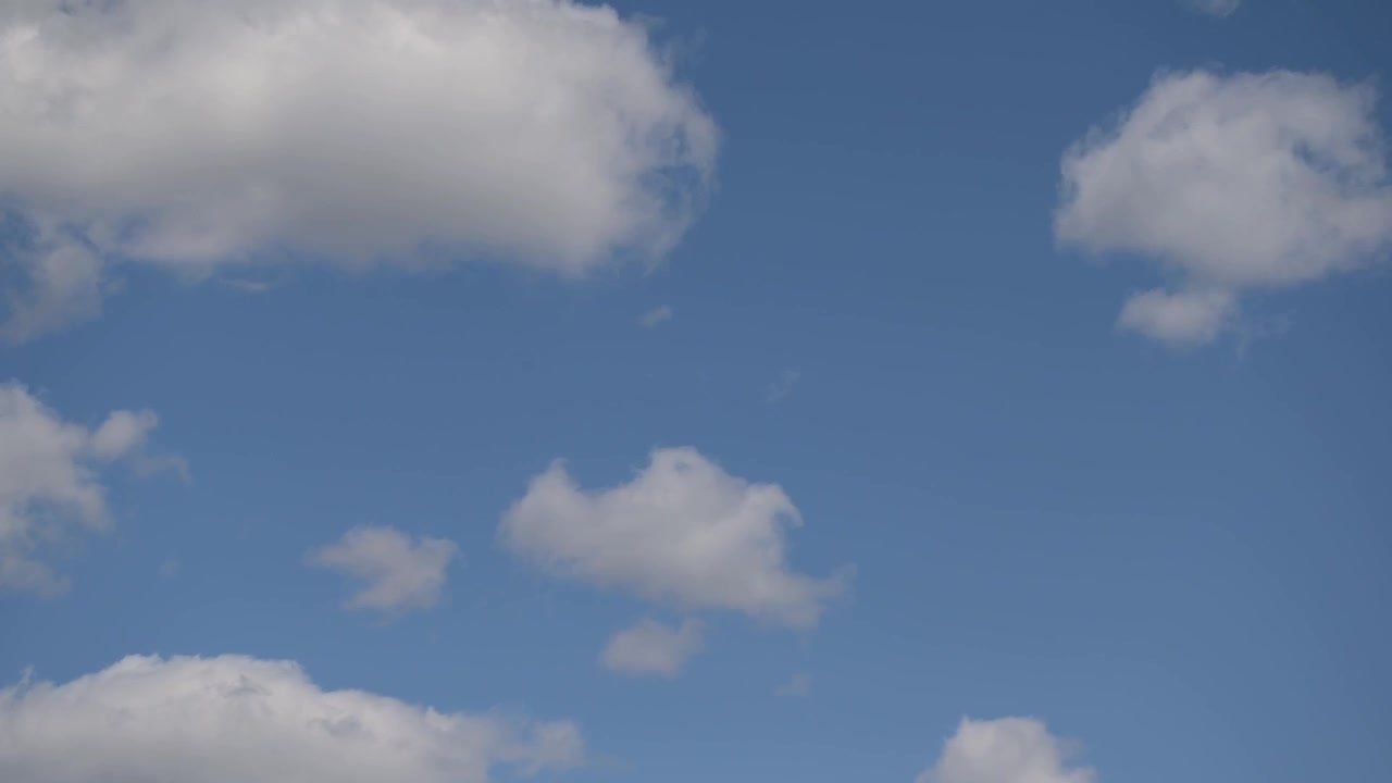 Clouds move from the top toward the bottom of the frame in timelapse, shifting from bright to darker tones while patches of blue sky remain visible between formations.
