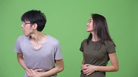 young asian couple having stomach ache together