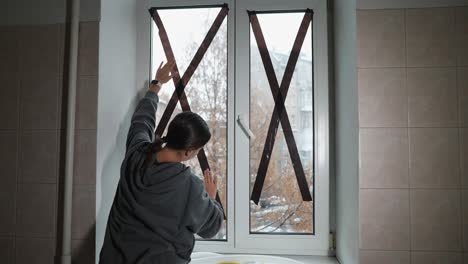 mujer reparando una ventana rota con cinta adhesiva