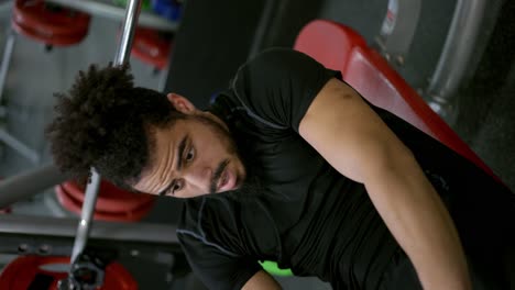hombre con físico musculoso pasa un duro entrenamiento levantando barra en el gimnasio
