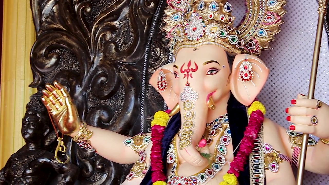 Idolo di Ganesha seduto su un trono dorato decorato con gioielli, durante il festival di Ganesh Chaturthi in un pandal a Mumbai, India, primo piano devozionale ornato