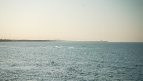 Beach-Shore-Coastline-At-Sunset-With-Small-Plane-Flying-Over-Horizon-In-Distance,-4K