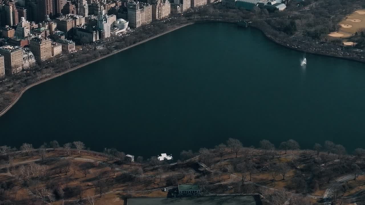 Vista di un lago a New York con edifici e alberi circostanti