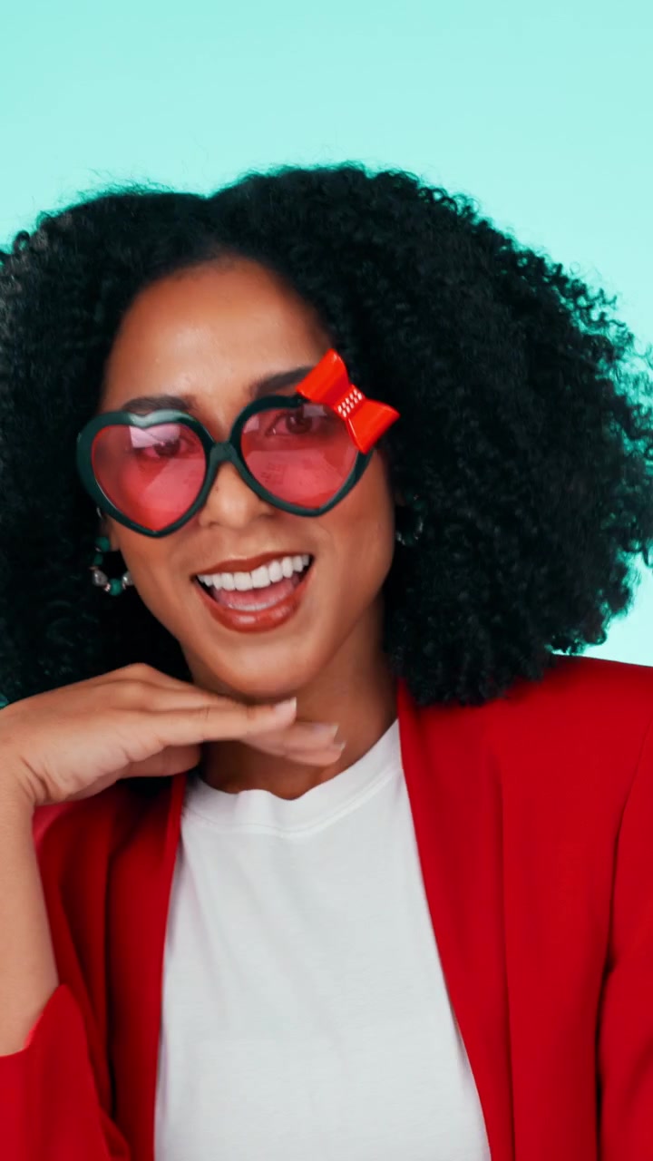 Stylish Woman Wearing Heart-Shaped Glasses Posing Against Teal Background