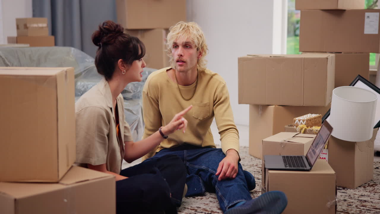 Young Couple Discussing Plans on Laptop While Sitting Among Moving Boxes