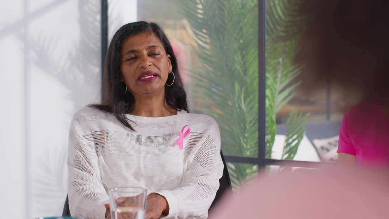 Mature Woman Wearing Pink Breast Cancer Awareness Ribbon Talking At Meeting Of Therapy Support Group For Cancer Treatment Patients 4