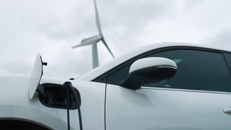 progressive combination of ev car, charging station and wind turbine.