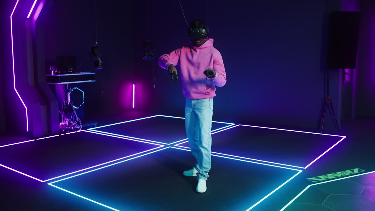 Uomo che gioca a un videogioco di realtà virtuale in una stanza illuminata al neon