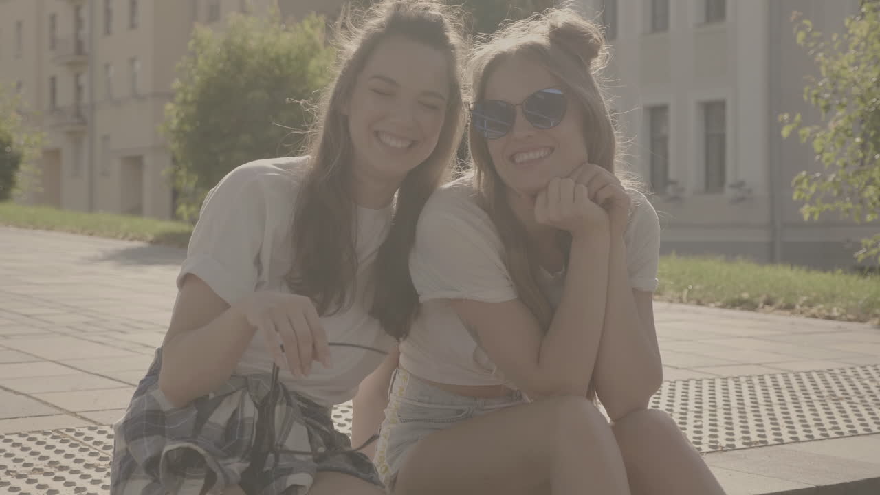 보행자 길 에 앉아 있는 두 명 의 행복 한 여자 들