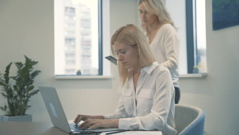 pretty female works with laptop, a coworker shows her some business documents