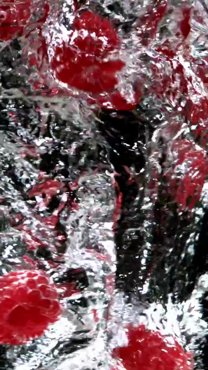 Vibrant Red Raspberries Splashing into Clear Water in Slow Motion