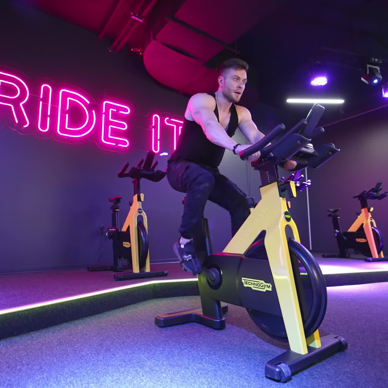 Man exercising in fitness club. Muscular athletic bodybuilder fitness man sitting stationary bicycle in gym
