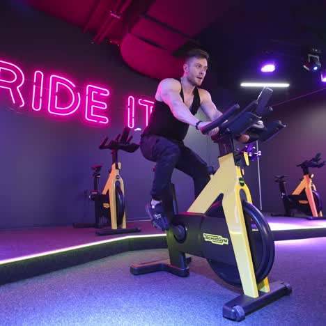 man exercising in fitness club. muscular athletic bodybuilder fitness man sitting stationary bicycle in gym