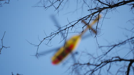 toma de seguimiento de un helicóptero de rescate alemán adac desenfocado que vuela sobre árboles en un cielo azul en misión de rescate