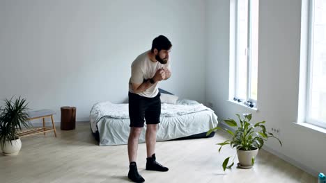 joven barbudo entrenando en casa, girando sus caderas