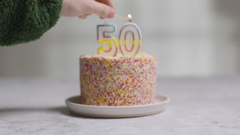 bolo de aniversário de foto de estúdio coberto com enfeites e vela comemorando o quinquagésimo aniversário sendo aceso