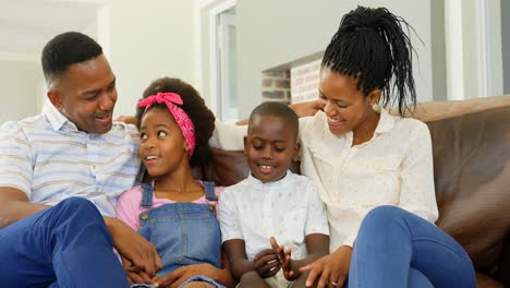 Vista-Frontal-De-Una-Joven-Familia-Negra-Sentada-En-El-Sofá-En-Una-Cómoda-Casa-4k