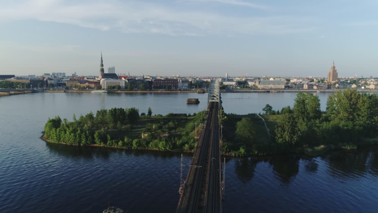 Cinematic aerial view reveals Riga skyline, railway bridge, Daugava River Latvia