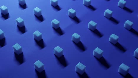 vista panorámica de izquierda a derecha de un fondo cúbico único con cubos de azúcar blanco dispuestos simétricamente en filas sobre un fondo azul oscuro, efecto 3d