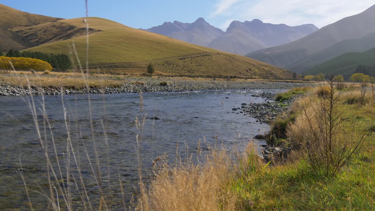 Pristine river flowing from the mountain and grassy hills in autumn