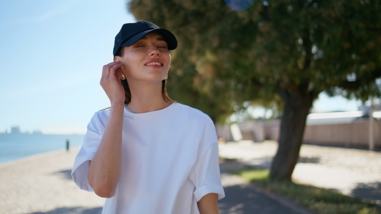 Relaxed lady listening music in earbuds at sunny street closeup. Happy girl