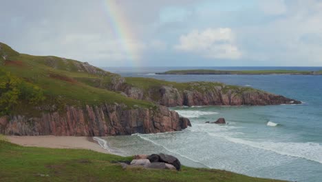 Surfer-camping-in-a-tent-on-the-top-of-the-cliff-overlooking-a-cold-and-rugged-beach-in-the-Scottish-highlands