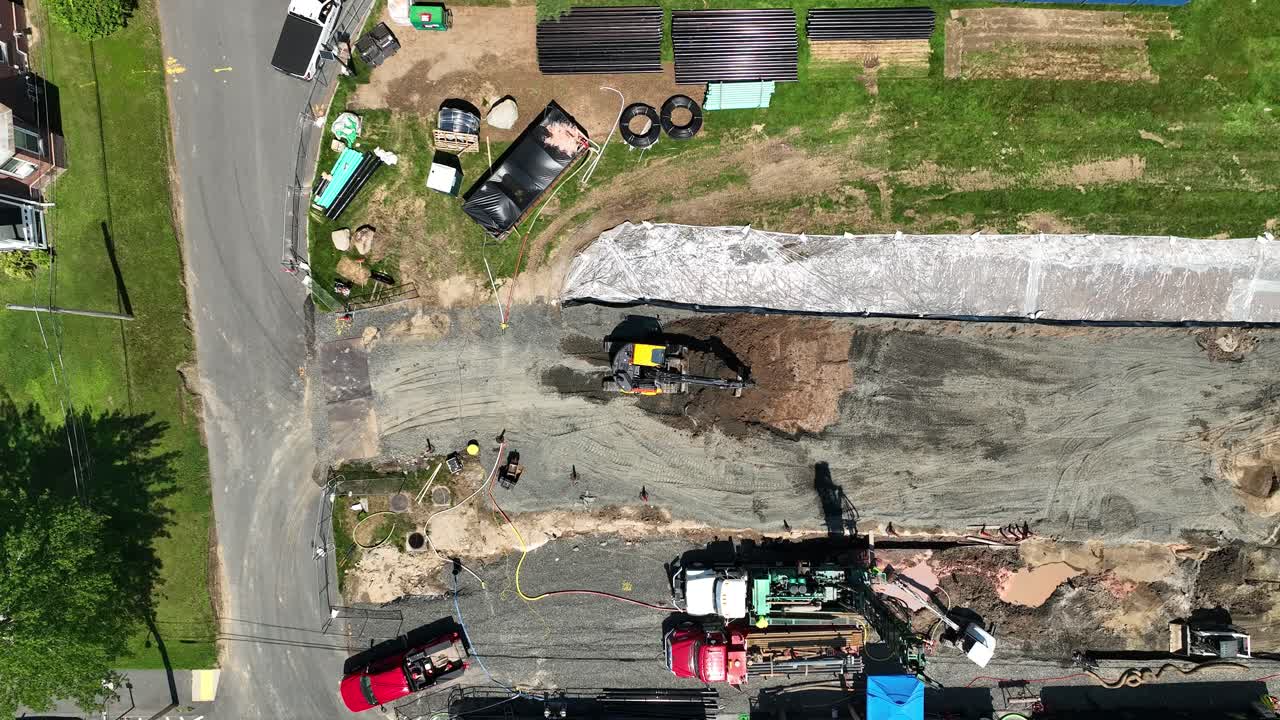 Drone top down static of excavator spinning and scooping dirt from pit on sunny day