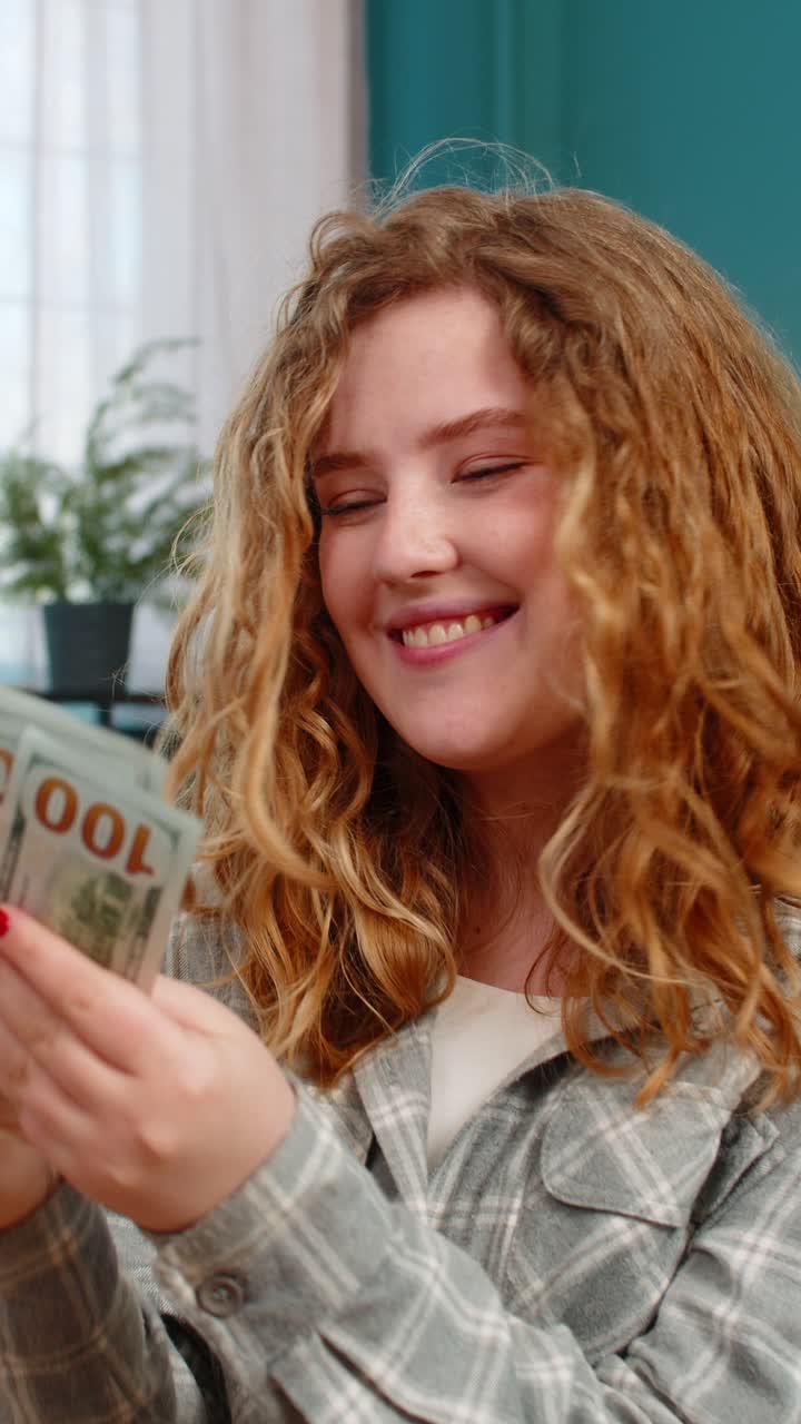Woman sits on sofa excitedly counting cash dollars celebrating lottery win or unexpected income joy