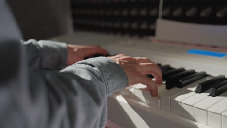 una foto elegante de una mano con una camisa de manga azul tocando el piano, con un fondo borroso que destaca el enfoque del artista