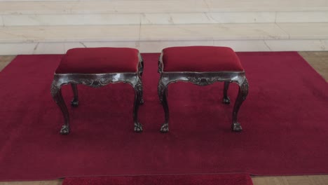 pair of antique prayer benches on deep red rug in sacred setting