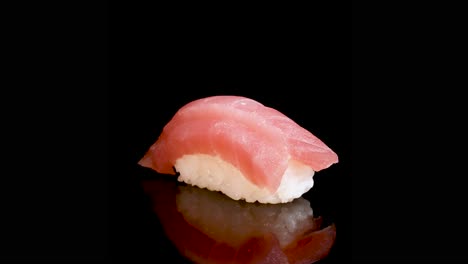 tuna sushi nigiri rotates smoothly on a glossy black background, highlighting texture and freshness with even, soft lighting and seamless camera movement