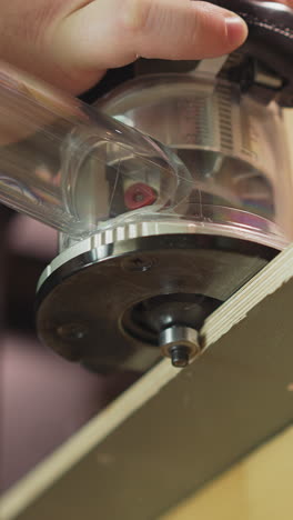 master polishes edge of plywood detail with electrical tool in workshop close low angle shot. furniture manufacturing technology at carpentry