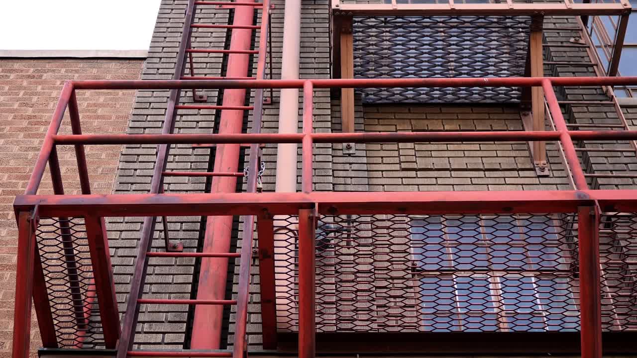 lenta panorámica mirando hacia una salida de escape de incendios en un clásico histórico hermoso edificio del centro de la ciudad, termina con la vista girando hacia el cielo