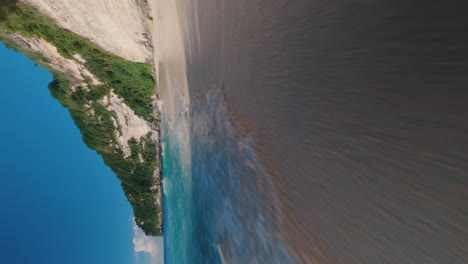 Vertikale-Low-FPV-Drohne-Schoss-über-Den-Tropischen-Sandstrand,-Während-Die-Wellen-Tobten