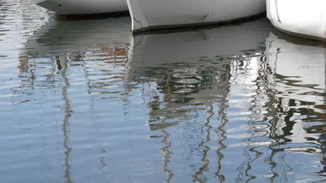 Details-of-sailboat-reflecting-on-rippling-water-surface,-close-up