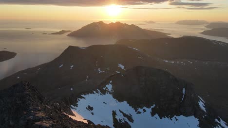midnight drone footage of the mountains and fjords of kvaløya in northern norway during midnight sun season
