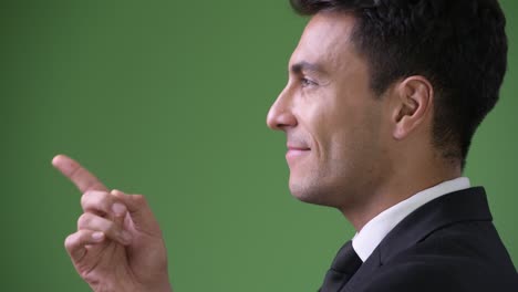 young handsome hispanic businessman against green background