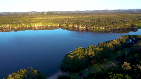 revealing drone shot from maritime forest over small pond to the beach and ocean at lennox head, near byron bay