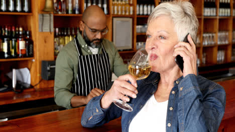 senior woman talking on mobile phone while having wine 4k