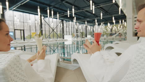 couple relaxing at a spa with cocktails by the pool