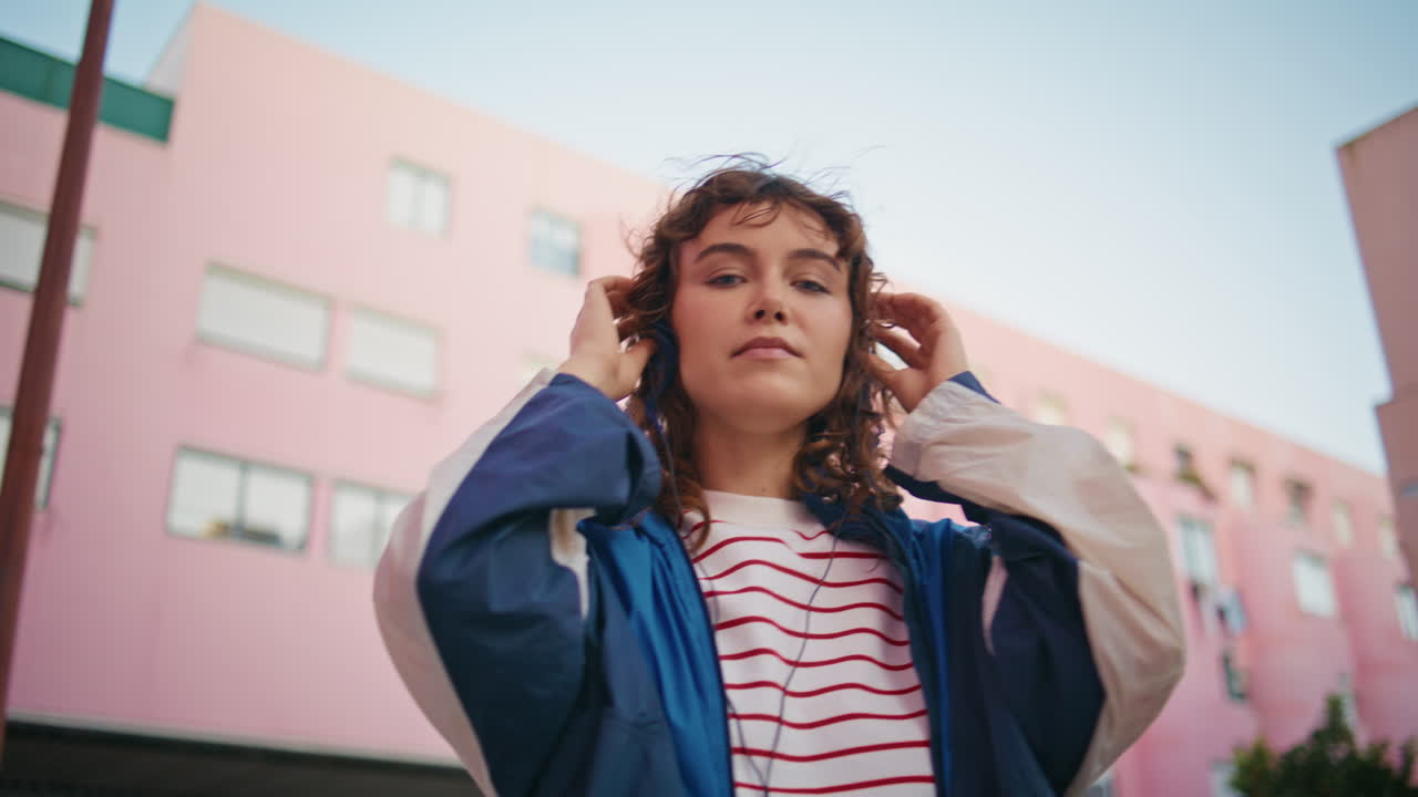 una mujer urbana bailando una canción con auriculares de cerca. una chica feliz escuchando música.