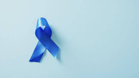 video of blue cancer awareness ribbon on blue background with copy space