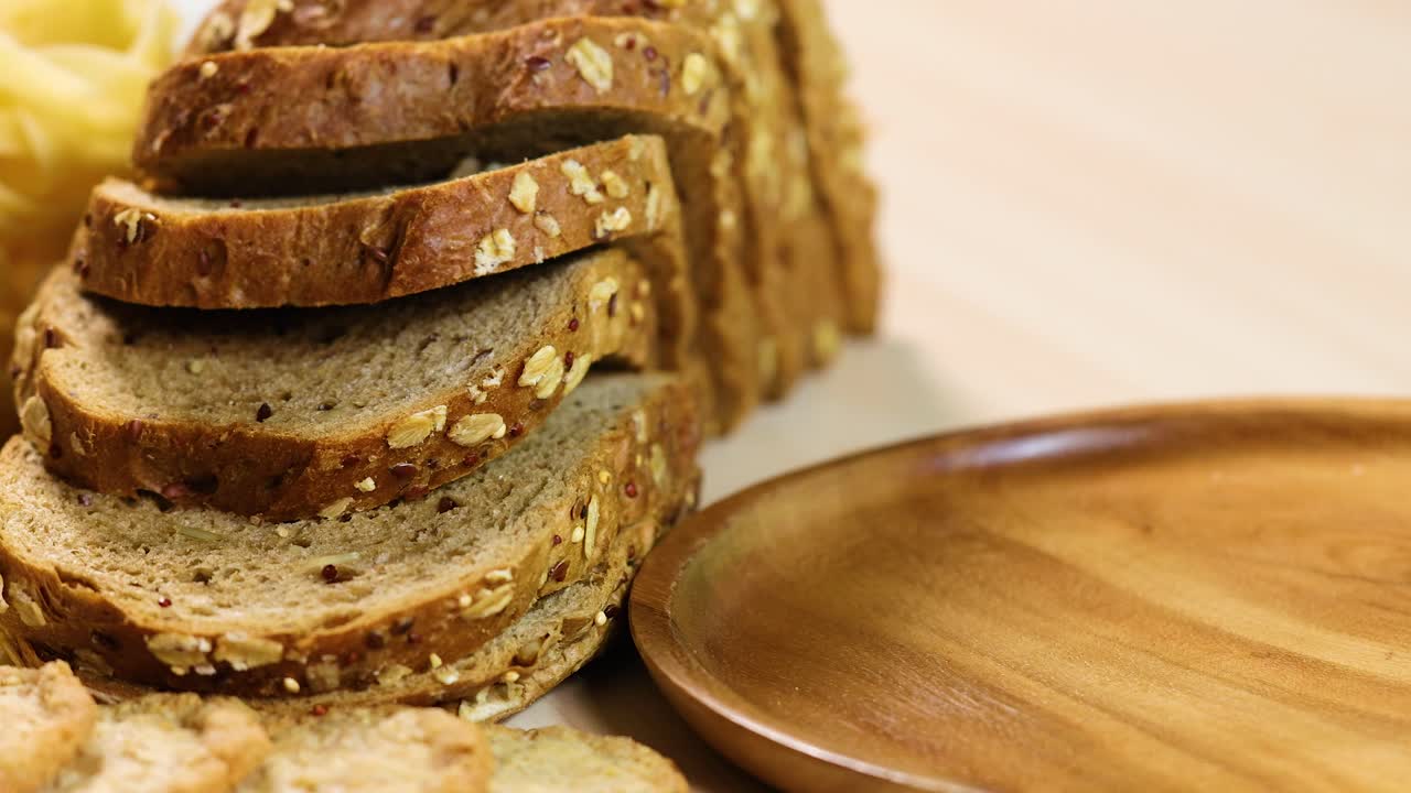 Whole wheat bread slices arranged beside a wooden plate in a well-lit kitchen setting