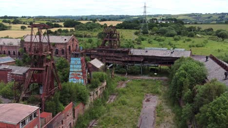 Verlassene-Alte-überwucherte-Kohlemine-Industriemuseum-Gebäude-Luftaufnahme-Langsamer-Aufstieg-Rechts