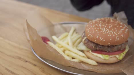 tasty burger with french fries on the plate. man's hand putting potato in ketchup and eating. shot in 4k