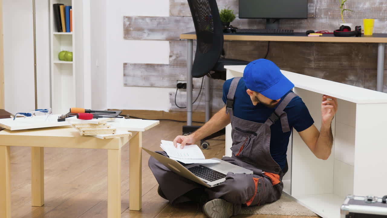 Man Assembling Furniture with Laptop and Instructions