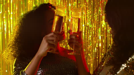 Close-Up-Of-Two-Women-Dancing-In-Nightclub-Bar-Or-Disco-Drinking-Alcohol-With-Falling-Gold-Confetti