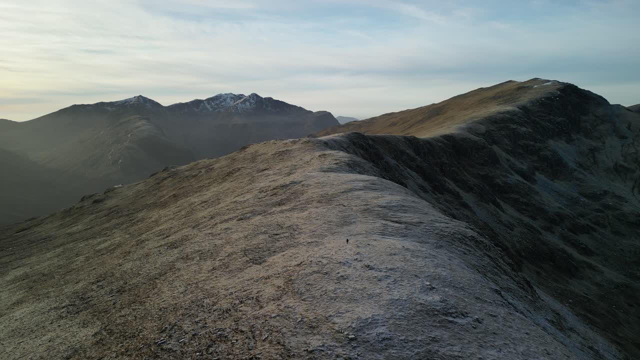 Glen Coe, Highlands scozzesi - vista aerea invernale sulle montagne, con un escursionista in cammino lungo la cresta che appare piccolo nell'ampio paesaggio