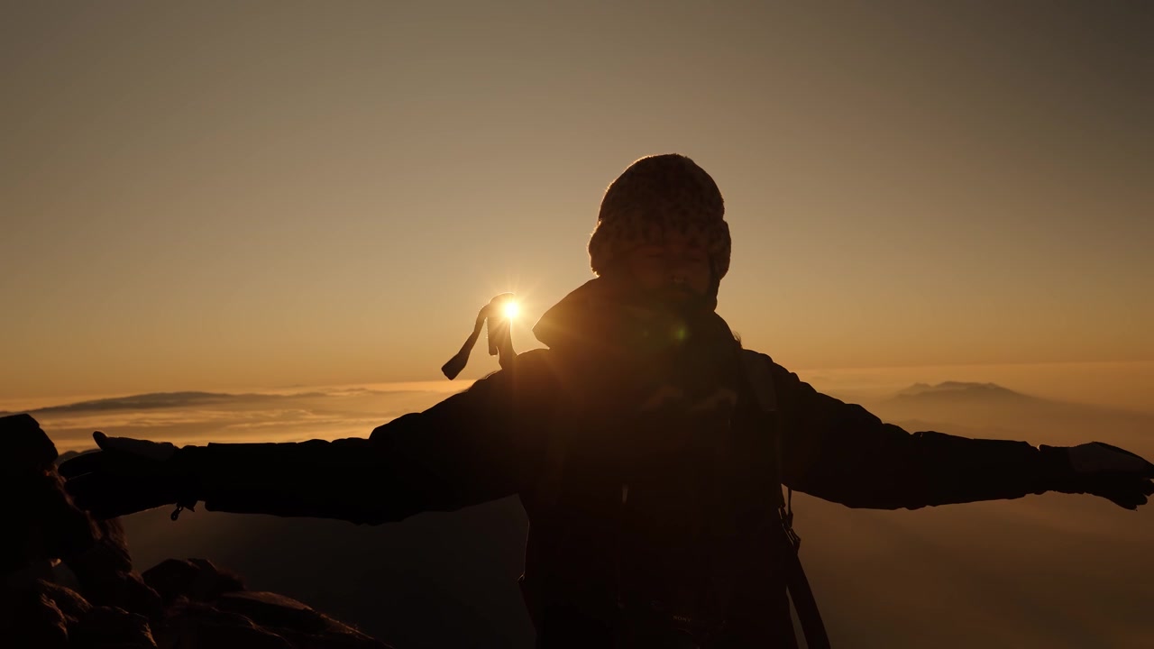 Hiker silhouette at sunrise on Acatenango summit above clouds Guatemala