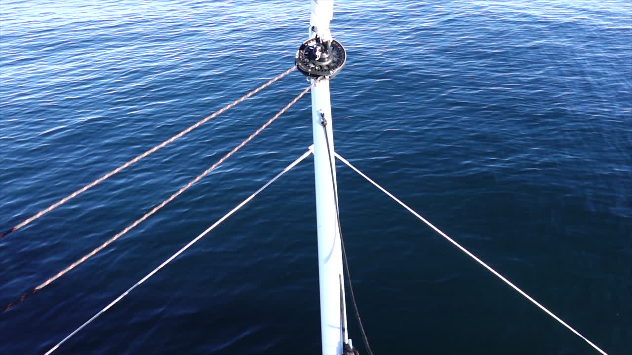 Close up shot of the pulpit and bow of a sail boat sailing over calm sea